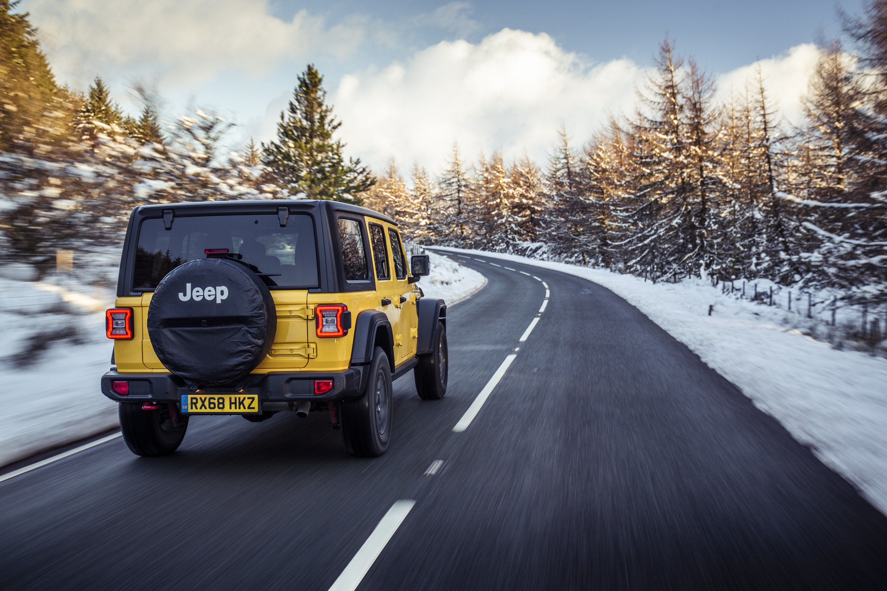 Rear view of Jeep Wrangler driving on a road